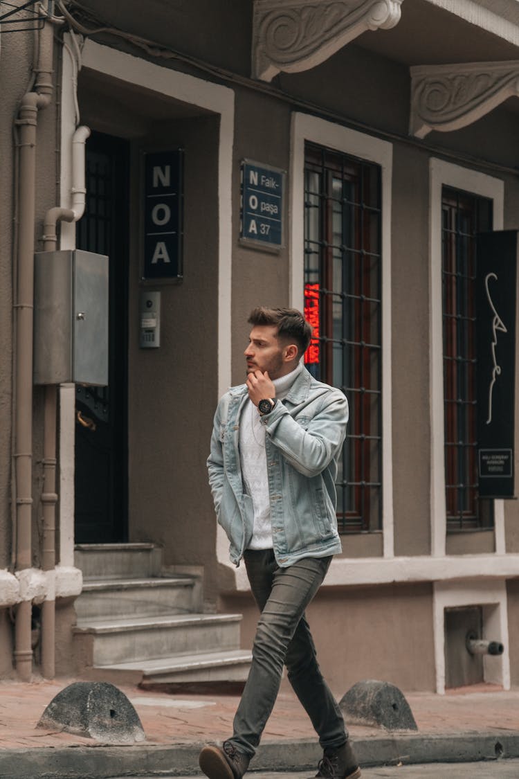 A Man In Denim Jacket Walking On The Street