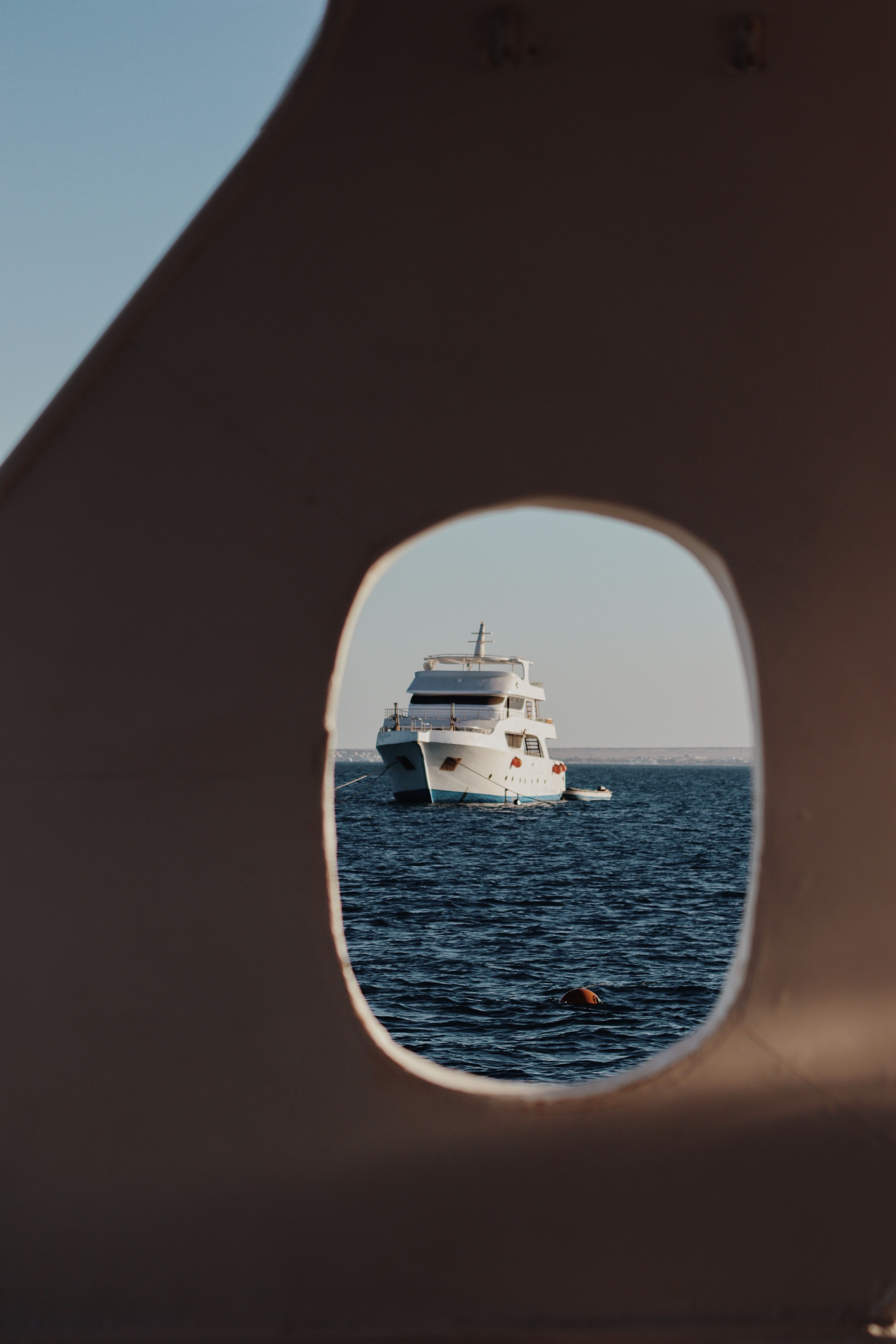 A yacht seen through a porthole on the Red Sea in Hurghada, Egypt, showcasing a nautical adventure.