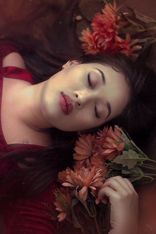 Woman Sleeping Beside a Bunch of Flowers