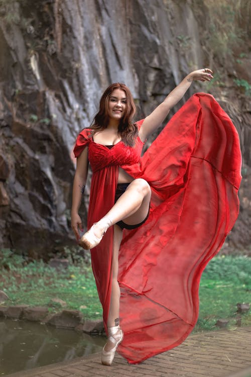 Woman in Red Dress Dancing Beside a Pond
