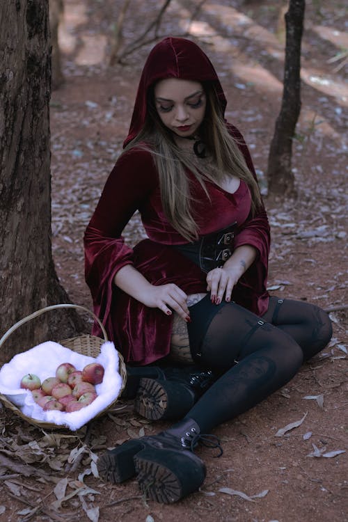 Woman in Red Riding Hood Costume Sitting Beside a Tree
