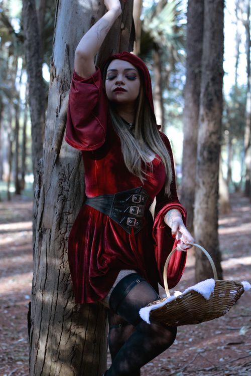 Free Woman in red riding hood costume posing in a forest setting, evoking fairy tale vibes. Stock Photo