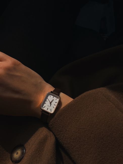 Close-up of a stylish wristwatch on a person's wrist, bathed in warm light, showcasing time with elegance.