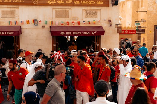 A bustling crowd of soccer fans celebrating in festive city streets with flags and vibrant attire.