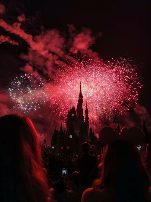 Free Vibrant nighttime fireworks explode over Disney castle, capturing a festive celebration with silhouetted spectators. Stock Photo