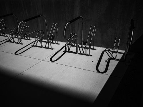 Free Artistic capture of empty bike racks casting shadows on concrete in stark black and white. Stock Photo