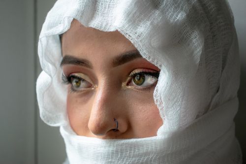Free Close-up portrait of a woman in a white headscarf and nose ring, conveying a mysterious vibe. Stock Photo