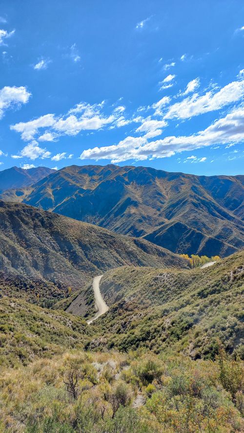 Free Scenic view of a winding road through Mendoza's mountains under a blue sky. Stock Photo