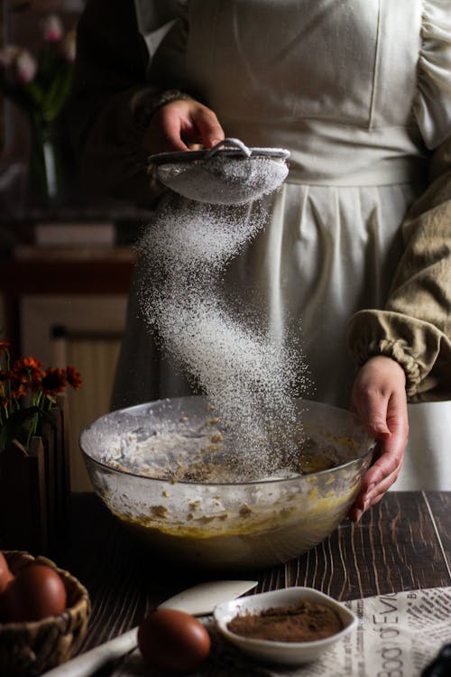 Woman Adding Powdered Sugar to Bowl