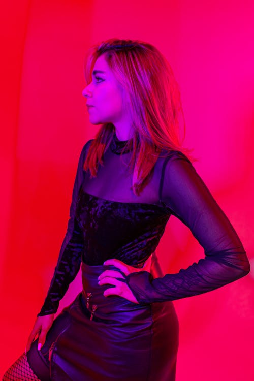 Model in Black Blouse and Leather Mini Skirt in Studio with Red Lighting