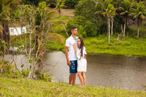 Free Couple standing by a peaceful riverside, embracing amidst lush greenery, conveying love and connection. Stock Photo