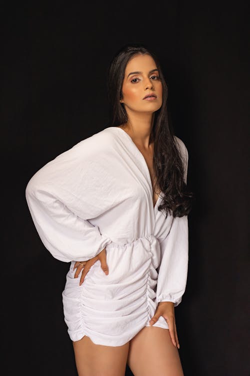 Young Brunette in a White Dress Posing in Studio 