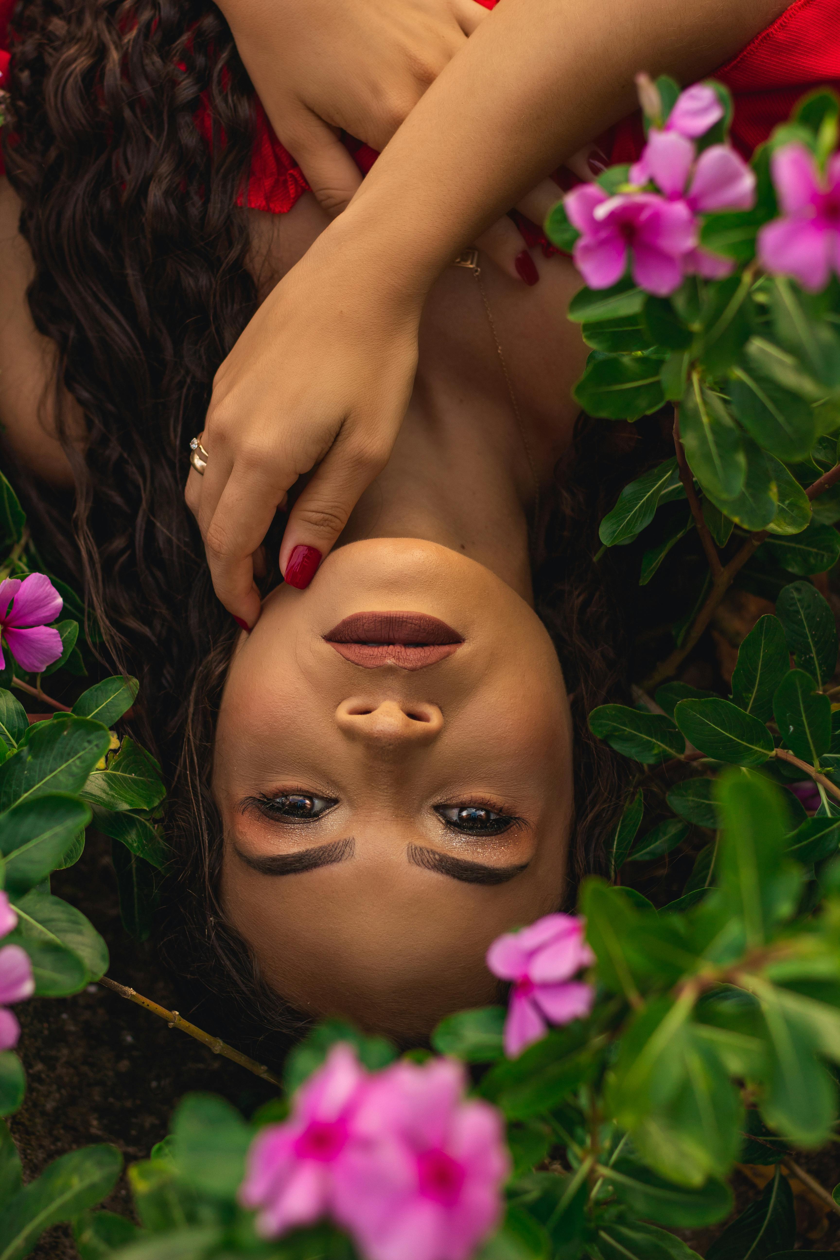 一个女人躺在郁郁葱葱的迷人肖像，充满活力的粉红色花朵，体现自然之美