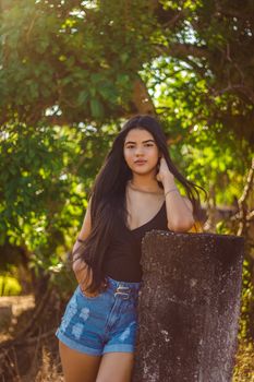 Casual pose of a young woman enjoying summer sunlight in a garden setting.