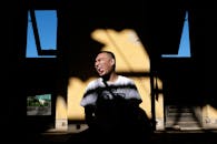 一个男人坐在阳光明媚的房间里，房间有独特的阴影和窗户，他正做着滑稽的鬼脸