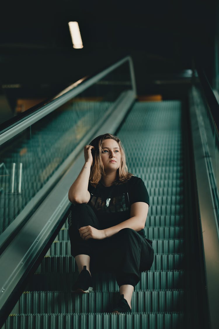 Woman Sitting On Escalator