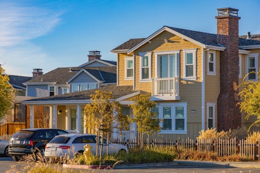 A picturesque suburban house with cars parked outside under a clear sky.