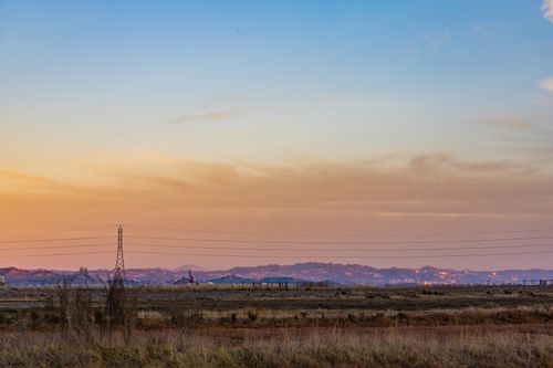 Free Serene landscape with a pastel pink sunset over open fields and distant hills, showcasing nature's tranquility. Stock Photo