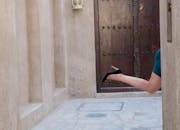 在迪拜，一名穿高跟鞋的女人从一扇质朴的木门旁的角落里，俏皮地伸出一条腿