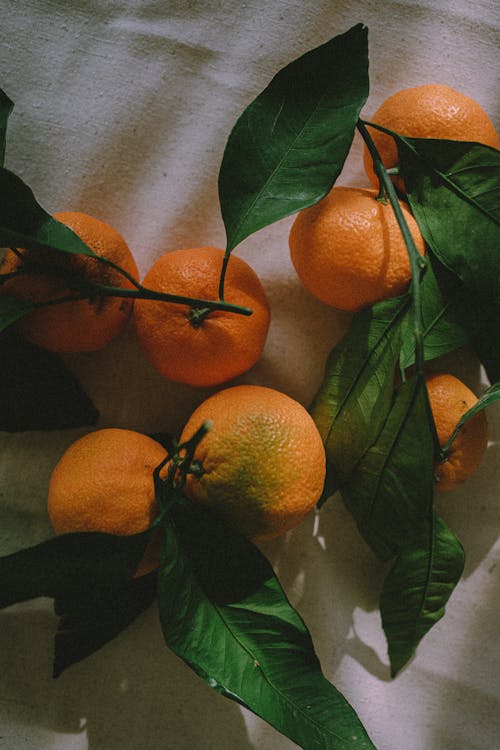 Close Up Photo of Oranges on White Textile