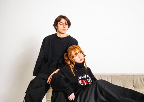Free A fashionable couple dressed in black sits and poses thoughtfully on a couch. Stock Photo
