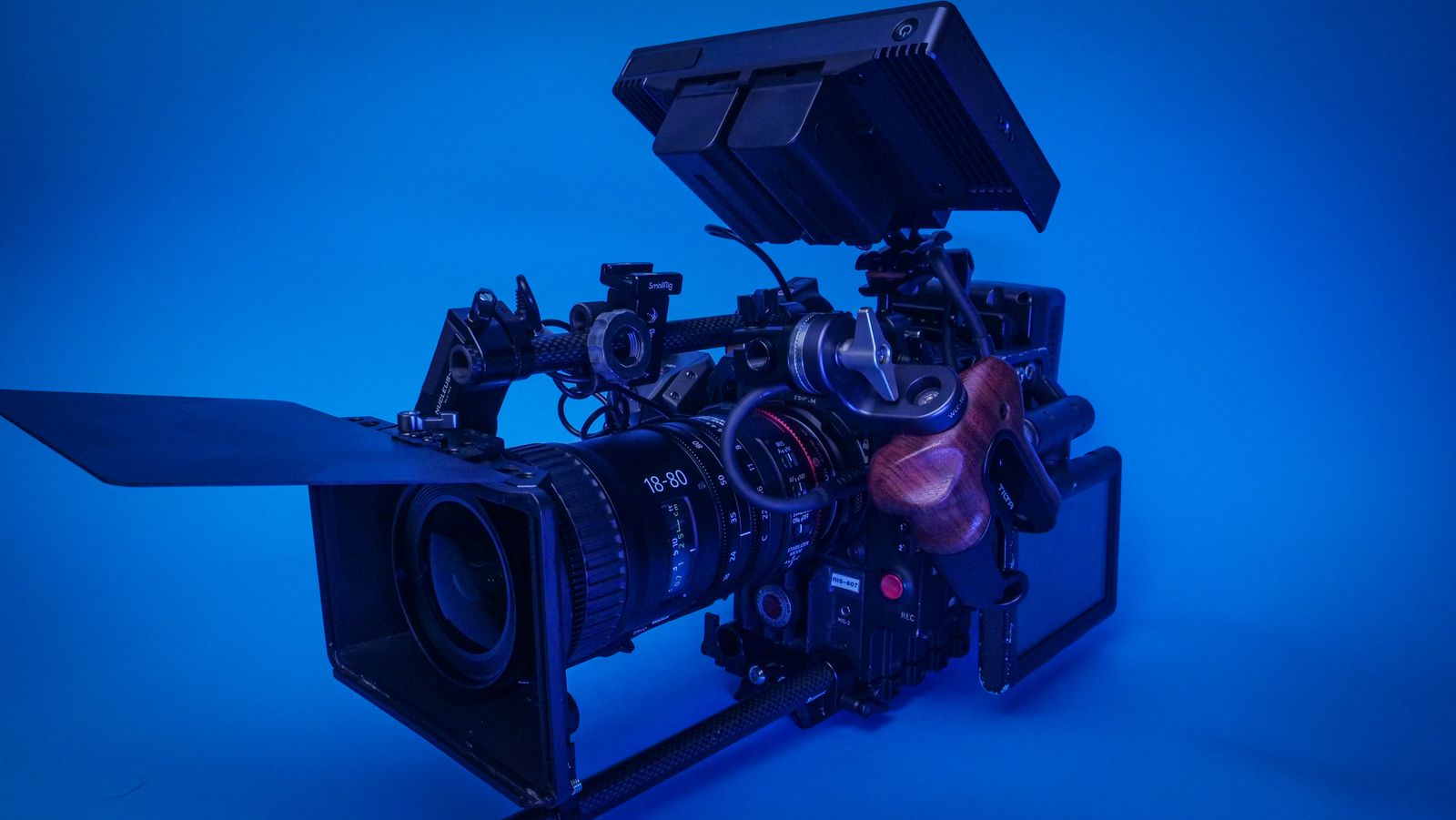 Professional cinema camera rig with lens, monitor, and matte box in blue studio light