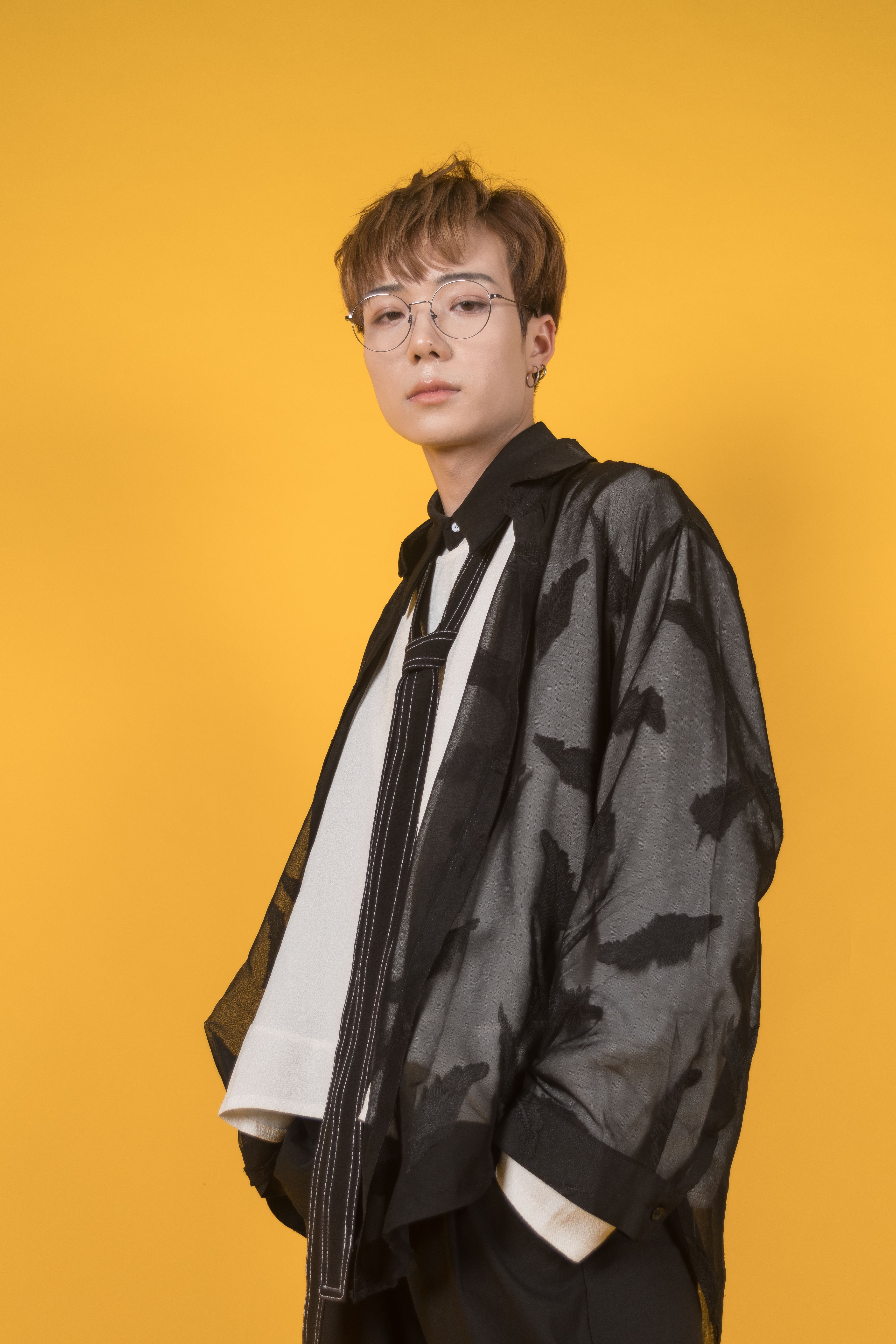 Fashion model wearing a trendy outfit against a vibrant yellow backdrop.