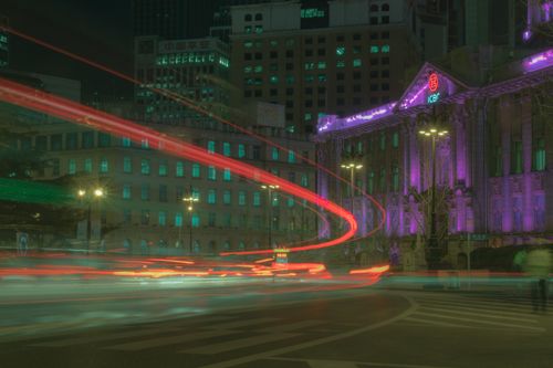 Free Dynamic city night scene with colorful light trails in front of illuminated buildings. Stock Photo