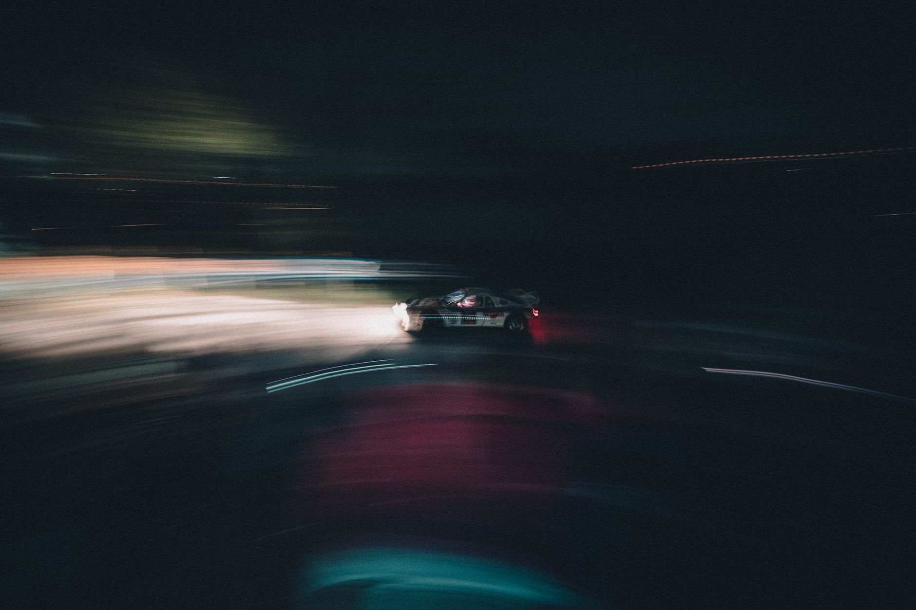 Blurred race car speeding on a night track in San Marino, capturing motion and excitement.