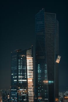 Nighttime view of illuminated modern skyscrapers with a dramatic urban skyline.