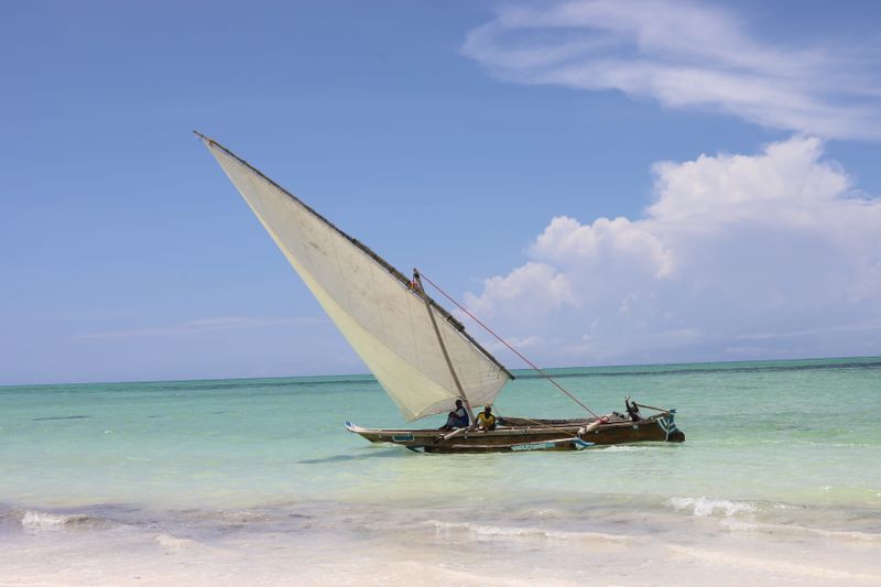 Dhow tradicional con vela triangular sobre aguas turquesa de Zanzíbar
