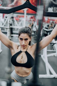 Athletic woman in sportswear using gym equipment, demonstrating strength and determination.