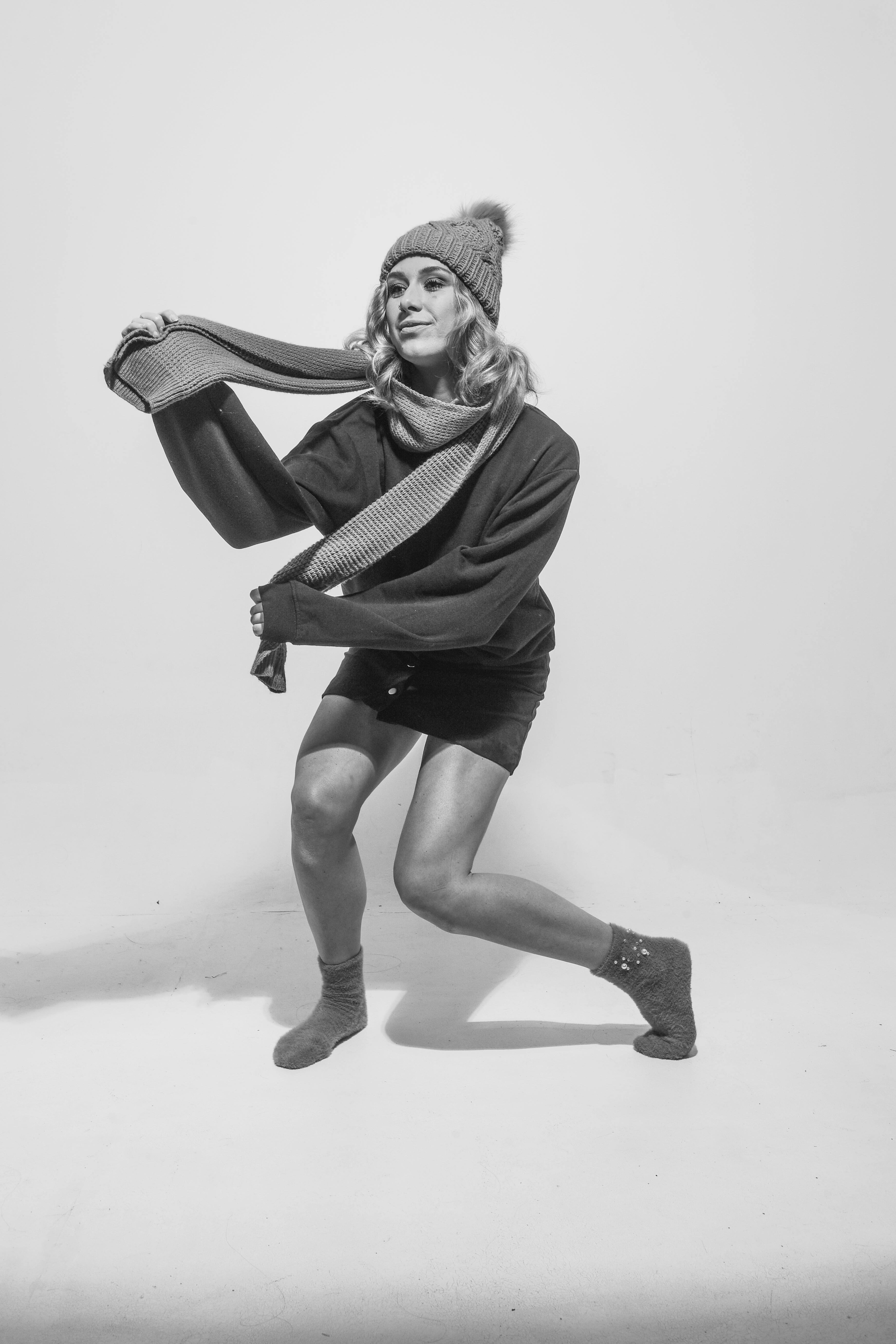 Free Black and white portrait of a woman in a knit hat and scarf striking a playful pose. Stock Photo