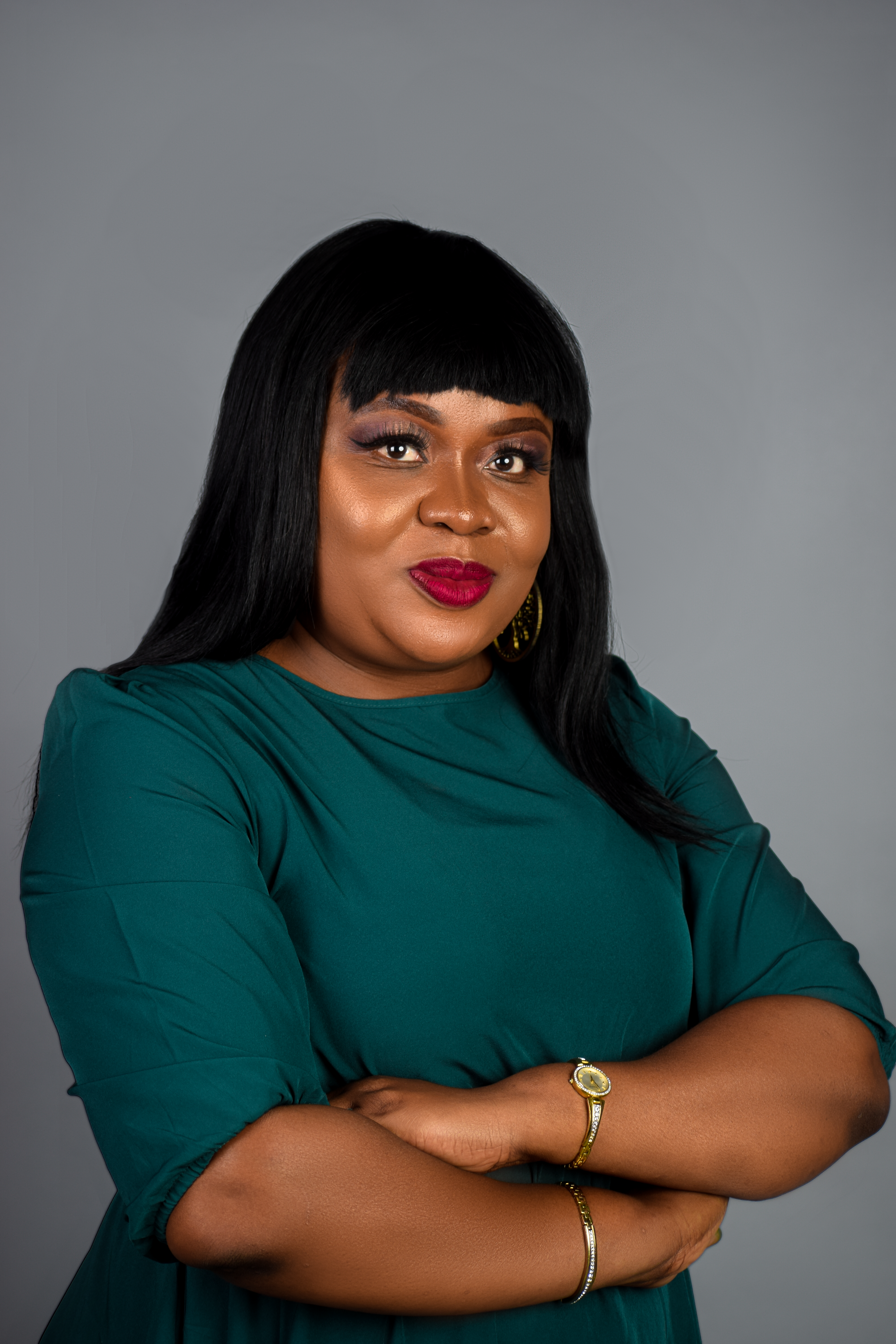 Portrait of a confident woman with arms crossed, smiling in studio with gray background. Captured in Pretoria, South Africa.