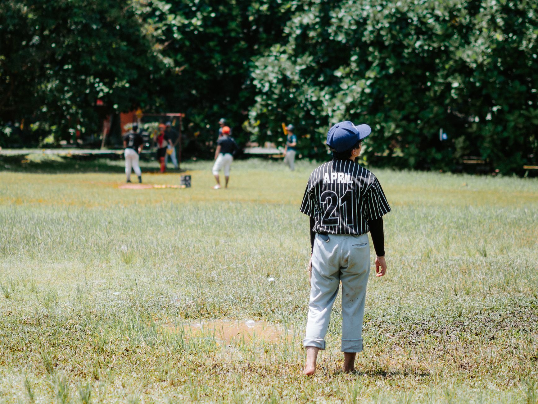 A group of kids enjoying a casual baseball game in a sunny park setting.