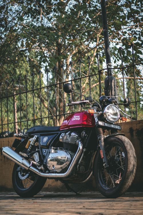 Free A classic Royal Enfield motorcycle parked beside a wrought iron fence on a sunlit street. Stock Photo