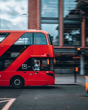 A vibrant red double-decker bus on the move in the bustling streets of London.