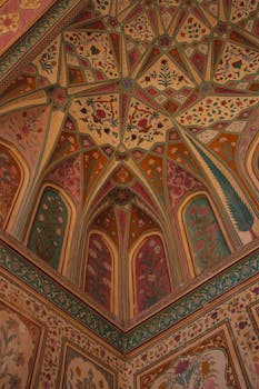 Stunning intricate ceiling artwork inside Sheesh Mahal, Jaipur, exhibiting vibrant floral patterns.