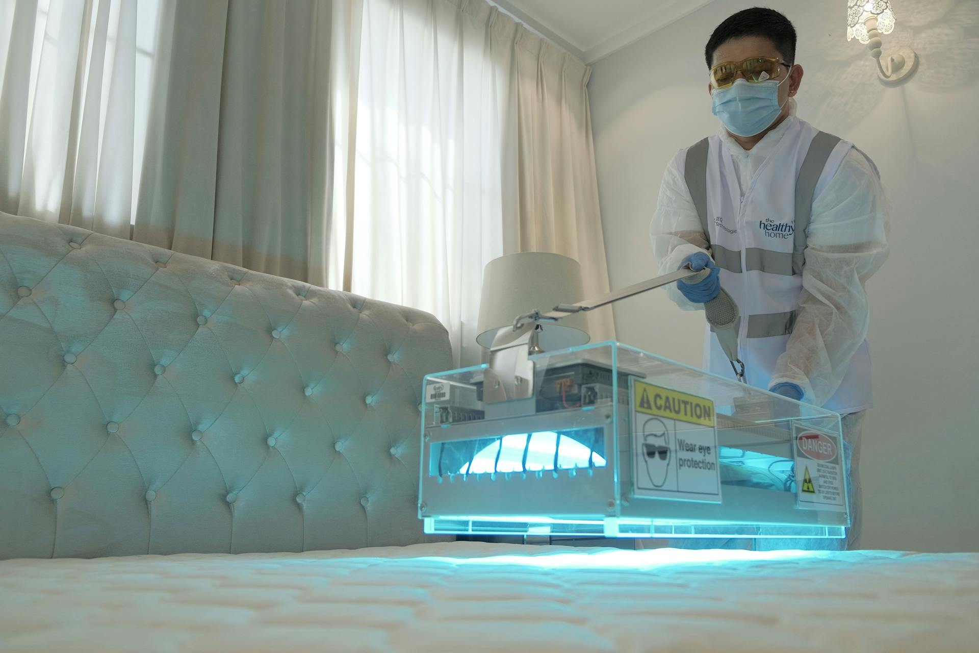 A Man Cleaning a Bed with Ultra Violet Light Sanitation