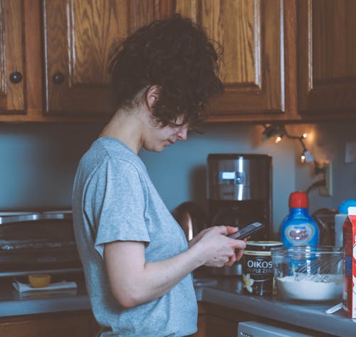 Woman Holding Smartphone in the Kitchen