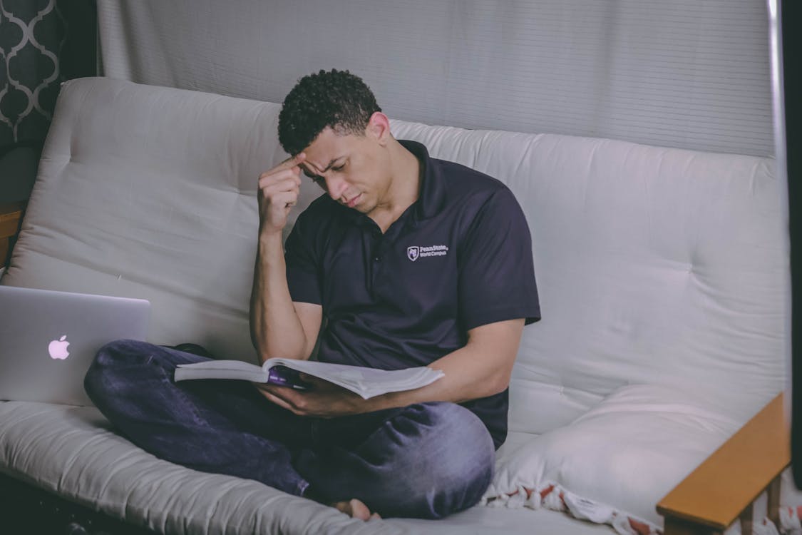 Free Man Sitting on Sofa Reading Book Stock Photo