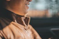 一个穿着棕色皮夹克的男人，沐浴在温暖的日光下微笑着