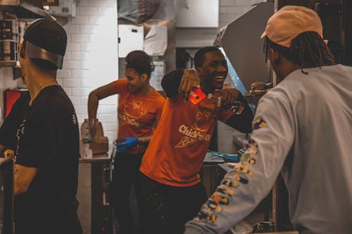 Mann In Orange Top Holding Smartphone