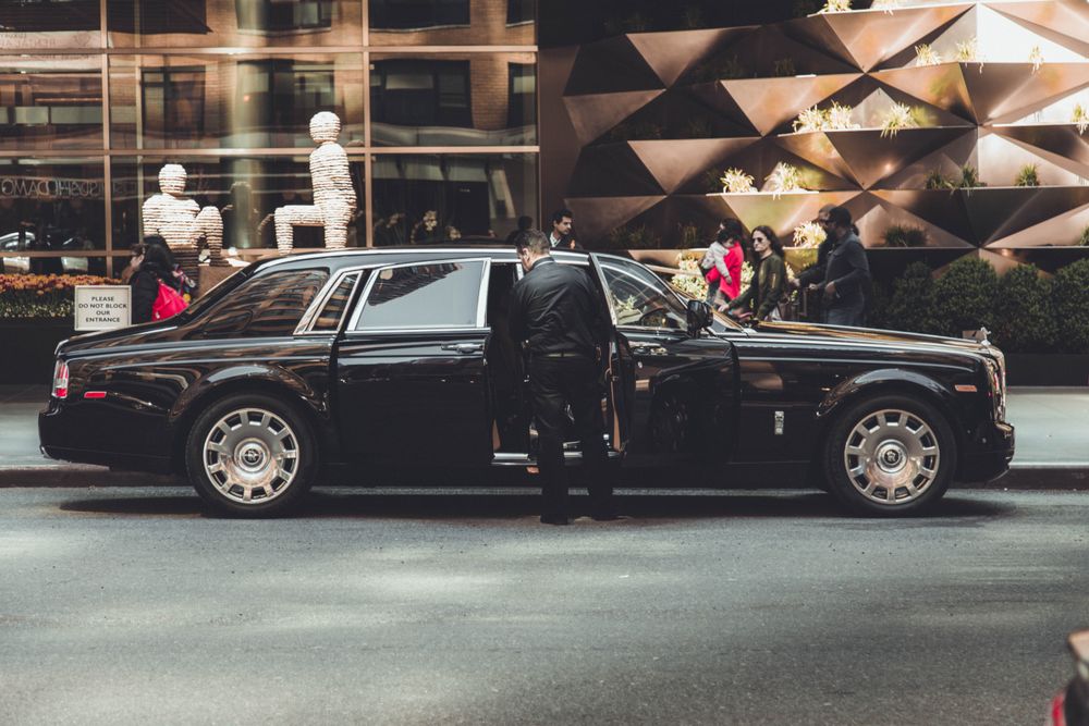 Chauffeur beside a luxury car, ready for customer car parking