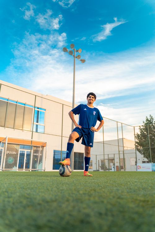 Free Teen soccer player poses confidently on football field in Bahrain. Stock Photo
