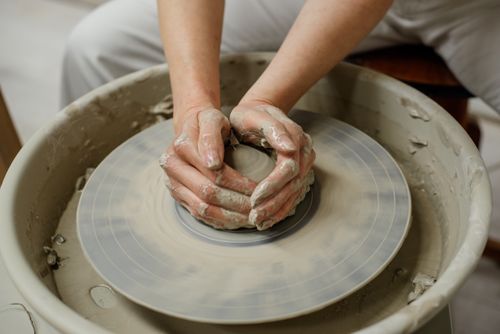 Free A woman skillfully molds clay on a pottery wheel, highlighting traditional artisan craftsmanship. Stock Photo