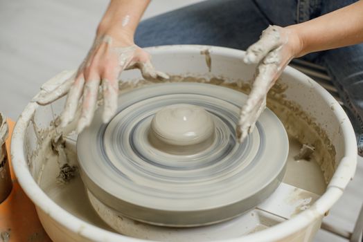 Close-up of hands sculpting clay on a pottery wheel, showcasing craftsmanship.