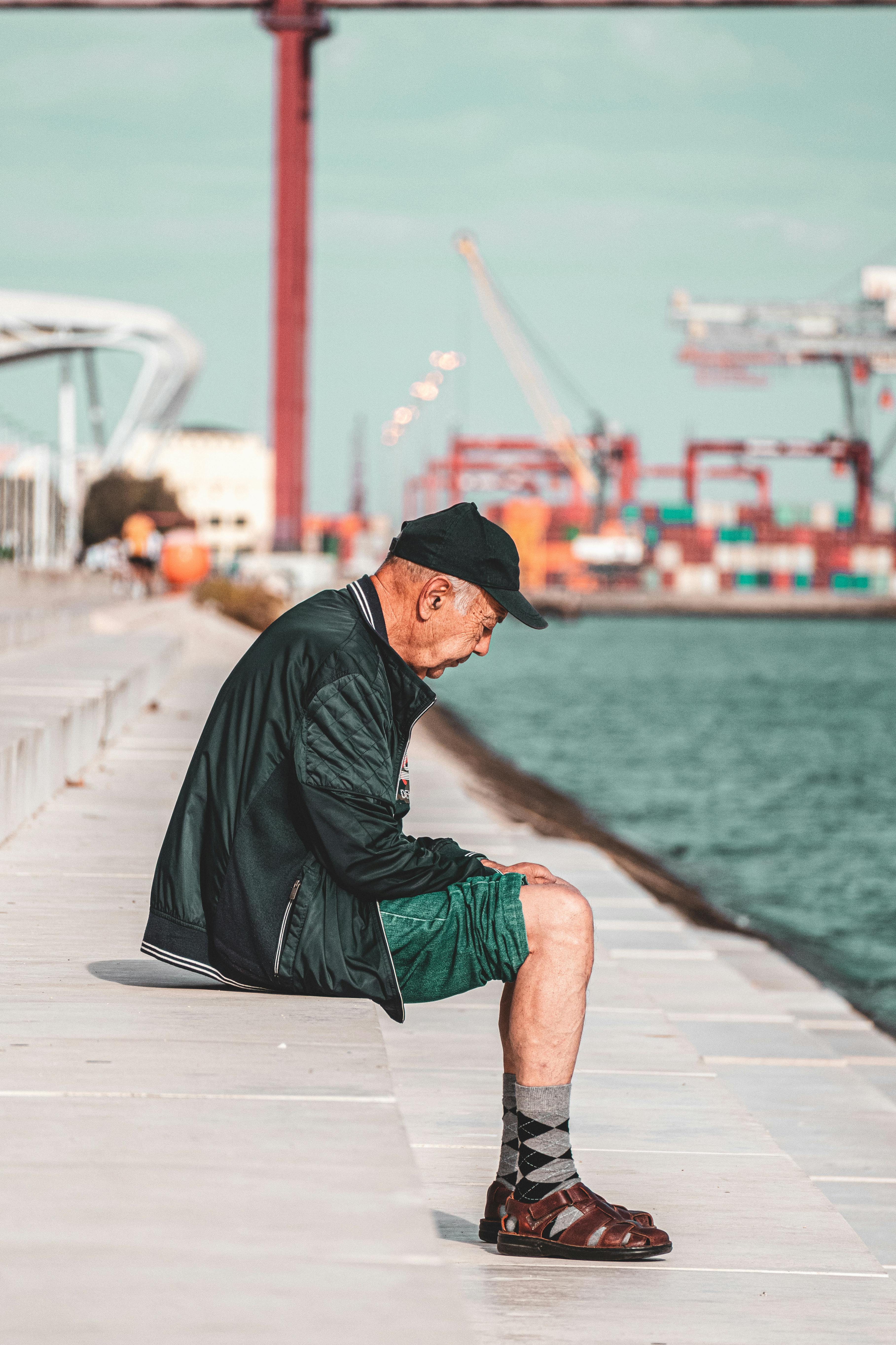 Portrait Of An Old Hunched Over Man Sitting By The River · Free Stock Photo