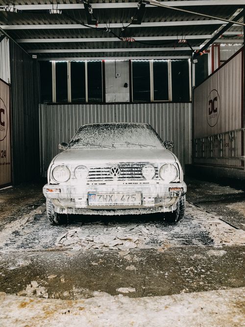Free Classic Volkswagen car covered in foam during wash at indoor garage. Stock Photo