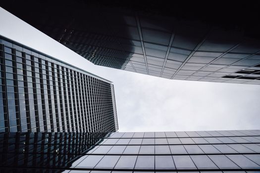 Low angle view of modern skyscrapers with glass facades and geometric reflections in London.